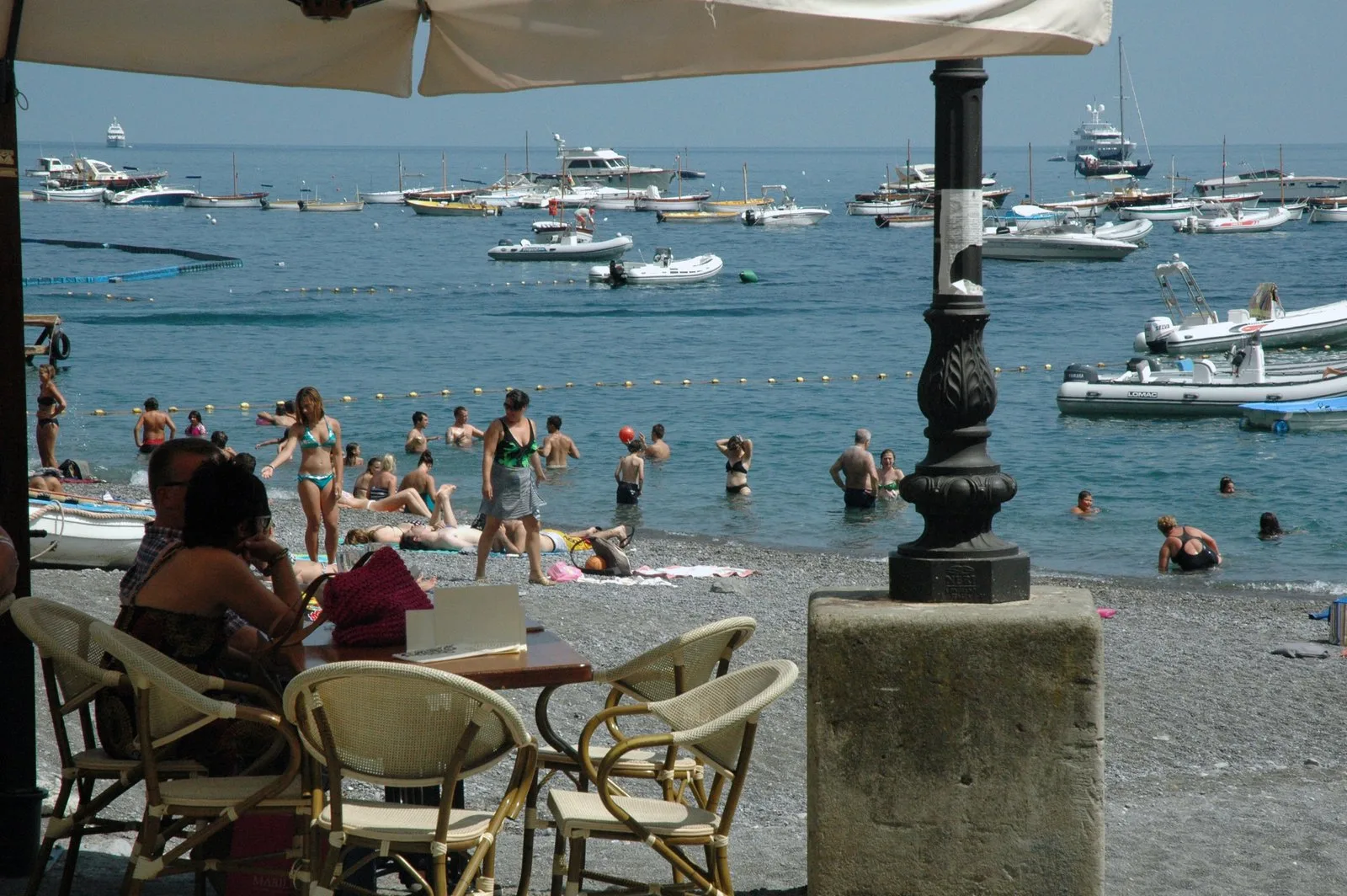 Người bơi và tắm nắng trên bãi biển Positano với thuyền trong vịnh