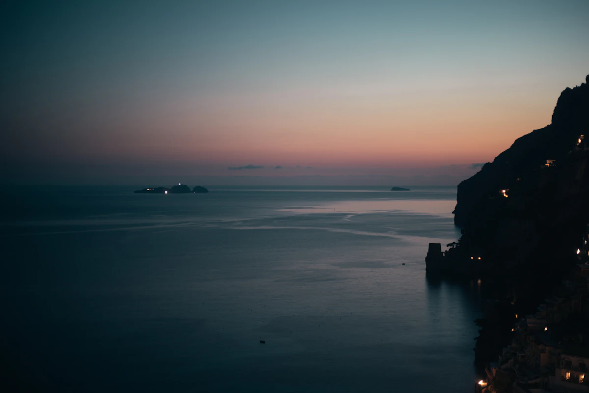 Positano rozświetlone wieczorem z restauracjami i oświetlonymi klifami
