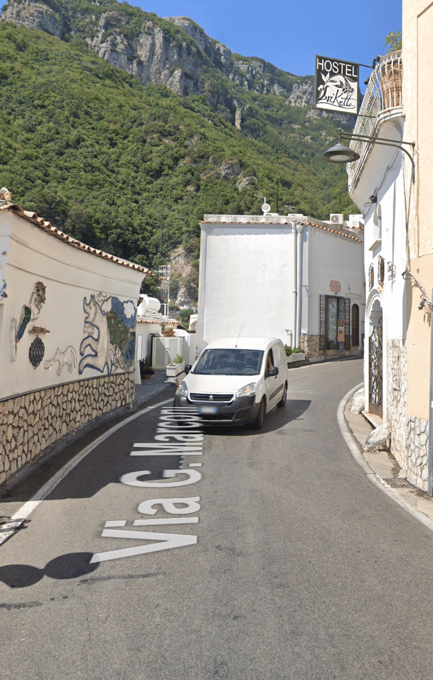 The road near Hostel Brikette with the hostel sign visible and the stairs to the entrance around the bend on the right.