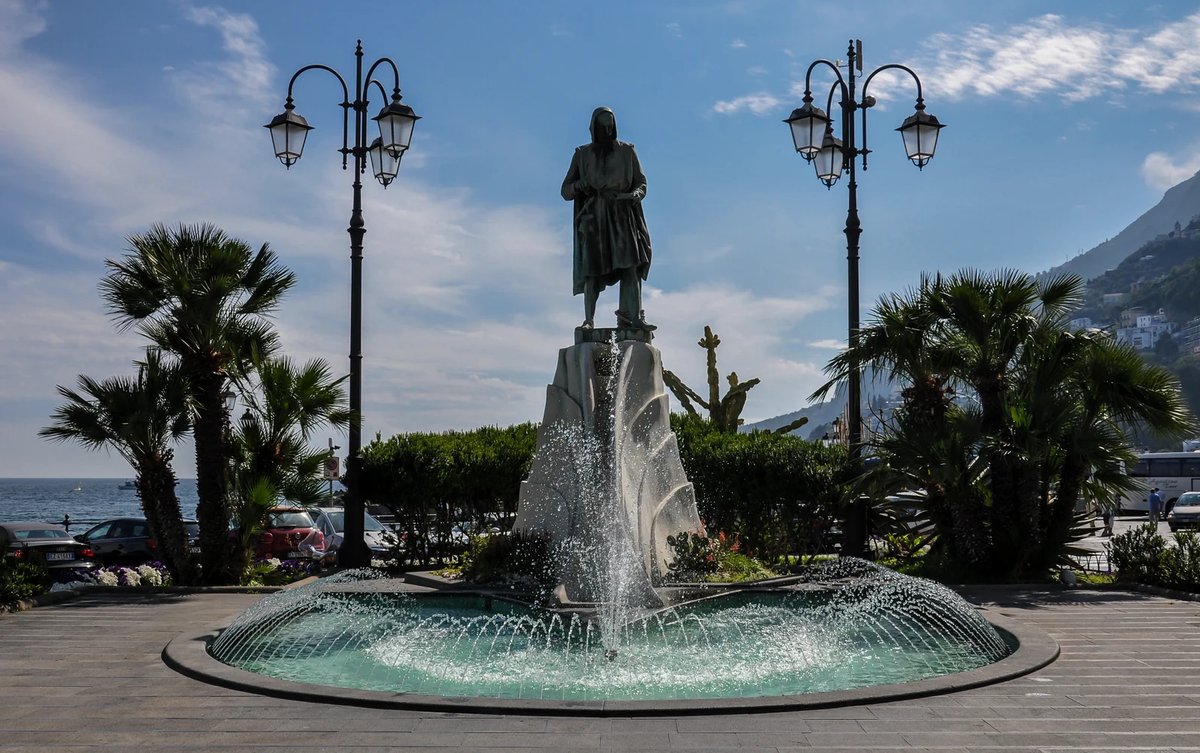 Piazza Flavio Gioia en Amalfi con la fuente y el área de parada de autobús cercana