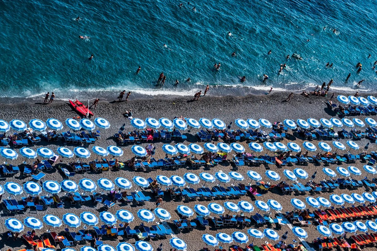 Filas de sombrillas en una playa de cantos rodados en Positano