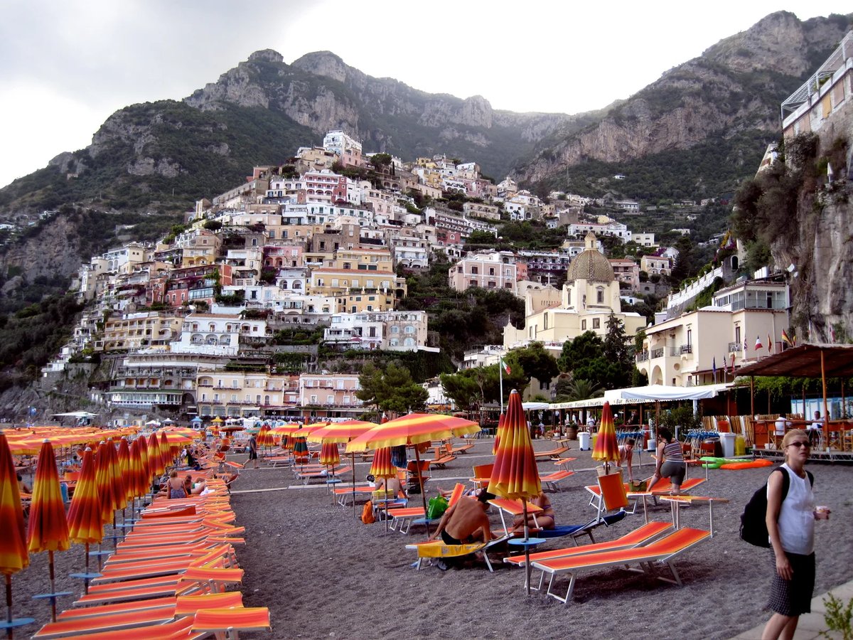 Vista panorámica de sombrillas en Positano y el pueblo subiendo por los acantilados