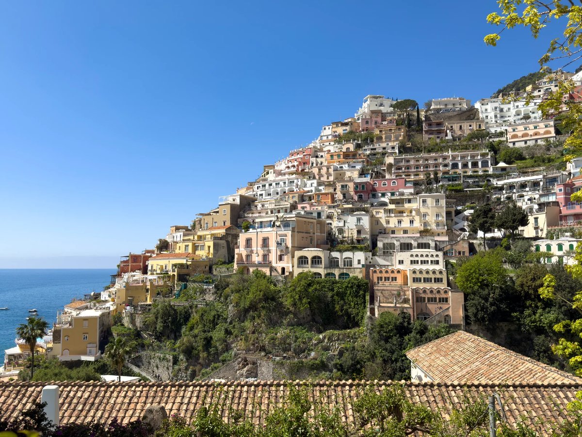 Vista panorámica de Positano desde el agua mostrando la playa Spiaggia Grande y el muelle