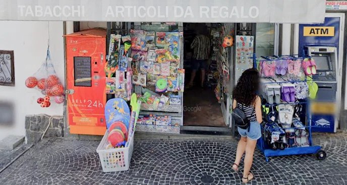 The tabacchi shop by the Chiesa Nuova bus stop with an awning that reads 'TABACCHI' and 'ARTICOLI DA REGALO'.