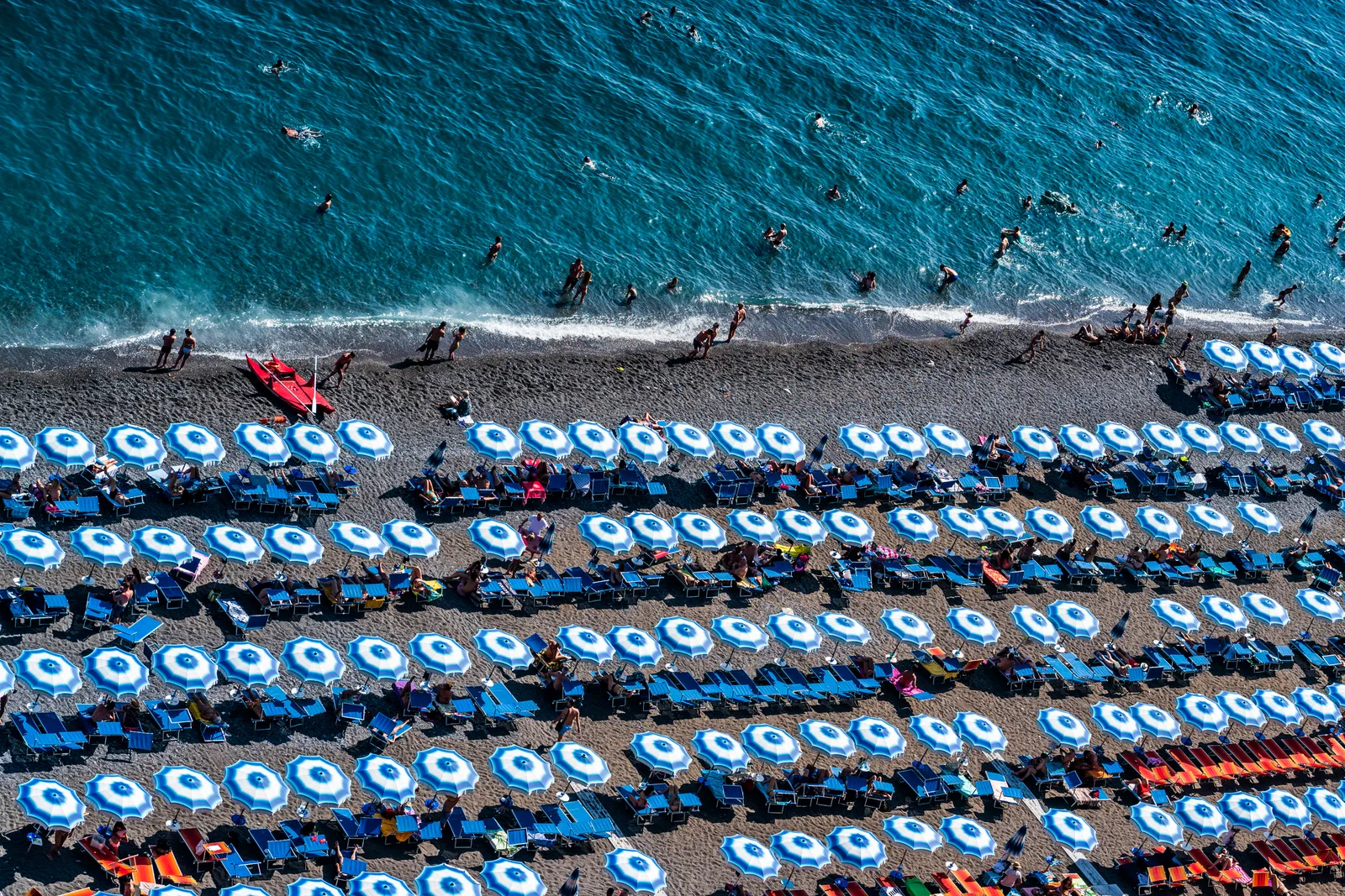Rækker af strandparasoller på en stenstrand i Positano